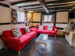 a living room with red couches and a fireplace at Rose Cottage in Upton upon Severn