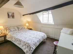 a bedroom with a bed and two tables and a window at Rose Cottage in Upton upon Severn