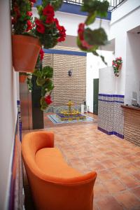 uma cadeira laranja no meio de uma sala com flores em Noches en Triana em Sevilha