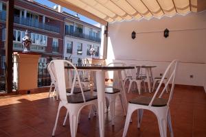 a dining room with a table and white chairs at Noches en Triana in Seville