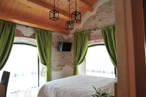 a bedroom with green curtains and a bed and windows at NUOVA FILANDA Rooms and More in Valdobbiadene