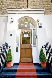 a front door of a white building with two plants at Leigh House Hotel in London