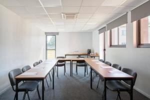 una sala de conferencias con mesas y sillas de madera en Best Western Hôtel Agen Le Passage, Agen Sud, en Le Passage