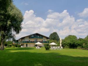 a large building with chairs and umbrellas in a yard at Hotel garni - Chiemsee-Pension-Seebruck in Seebruck