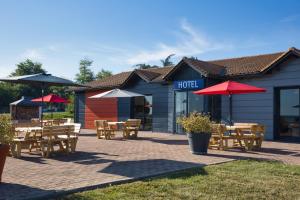 a hotel with tables and chairs and umbrellas at Best Western Hôtel Agen Le Passage, Agen Sud in Le Passage