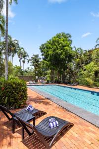 uma piscina com duas espreguiçadeiras ao lado em Frontier Hotel Darwin em Darwin