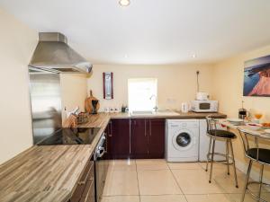 a kitchen with a washer and dryer next to a counter at Whispering Willows - The Thatch in Craigtown