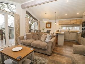 ein Wohnzimmer mit einem Sofa und einem Tisch in der Unterkunft Westbrook Lodge in Bowness-on-Windermere