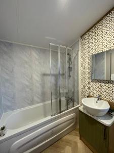 y baño con bañera, lavamanos y ducha. en Eastgate Lodge with Hot Tub, en Malton