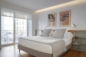 ein weißes Schlafzimmer mit Bett und Balkon in der Unterkunft Nautiko by FeelFree Rentals in San Sebastián