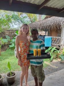 a man and a woman holding a tray of drinks at Yaye Guest House in Tissamaharama