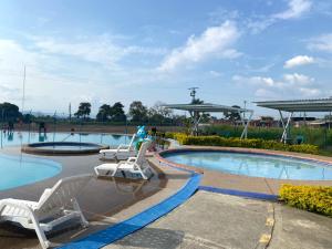 a swimming pool with two chairs and avisorvisorvisor at Apartamento turistico cerca al parque del café en Montenegro Quindío in Montenegro