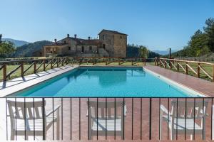 a swimming pool with two chairs and a house at Borgo Macereto in Dicomano