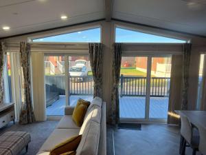 a living room with a couch and sliding glass doors at Blue Bell Lodge with Hot Tub Malton in Little Habton