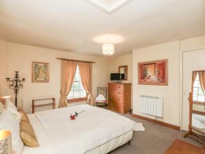 a bedroom with a large white bed and windows at Rose Cottage in Crosby