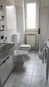 La salle de bains blanche est pourvue de toilettes et d'un lavabo. dans l'établissement Appartamento a Lecco sul Lago di Como, à Lecco