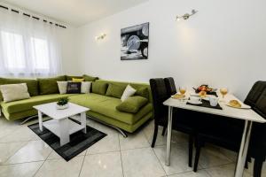 Bonaca in Kaštela - Dalmatien في قشتيلا: غرفة معيشة مع أريكة خضراء وطاولات