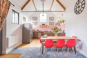 a kitchen and dining room with a table and red chairs at The Kennels by Bloom Stays in Faversham