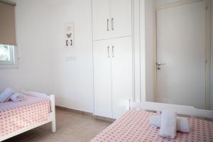 a white bedroom with two beds and a mirror at Protaras View Villas in Protaras