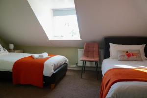 a bedroom with two beds and a chair and a window at Castle House Guest House in Dover