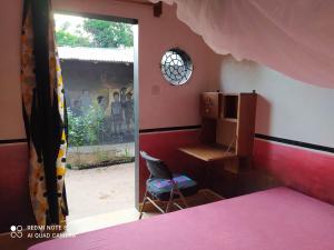 a bedroom with a bed and a desk and a window at Chez Yaya - Chambre Sousete in Oussouye