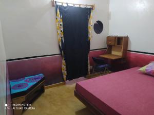 1 dormitorio con cama, escritorio y ventana en Chez Yaya - Chambre Sousete en Oussouye