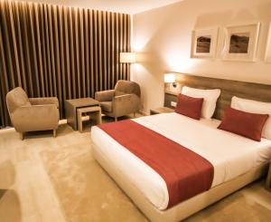 ein Hotelzimmer mit einem Bett und einem Stuhl in der Unterkunft Hotel Monotel Dar El Barka in Nouakchott