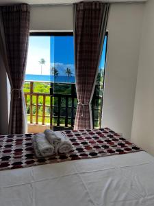 
a cat sitting on a bed next to a window at Villaggio Orizzonte in Salvador
