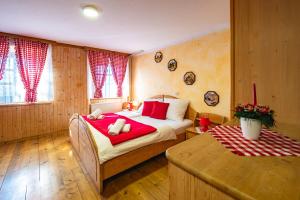 a bedroom with a bed with red sheets and a table at Slovenian Traditional Guest House in Begunje na Gorenjskem