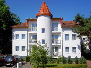 duży biały budynek z wieżą na górze w obiekcie "Am Schloonsee" Haus C w mieście Heringsdorf