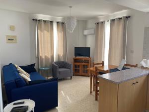 ein Wohnzimmer mit einem blauen Sofa und einem Tisch in der Unterkunft Riana Latchi Apartment in Polis Chrysochous
