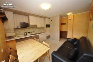 een woonkamer met een zwarte bank en een houten tafel bij Baita Carosello Apt 4 by Livigno Accomodation in Livigno +11 foto's