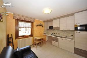 a kitchen with white cabinets and a table in it at Baita Carosello Apt 4 Adiacente Carosello 3000 in Livigno