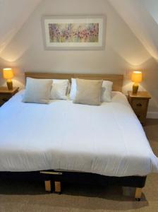 a bedroom with a large white bed with two lamps at Kingfisher Cottage, Port o Tay in Pitlochry