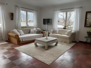 a living room with two couches and a table at Villa am Bach in Unterwössen