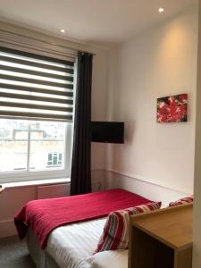 a bedroom with a red bed and a window at Rushmore Hotel in London