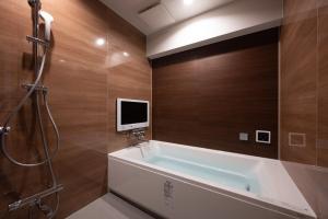 ein Badezimmer mit einer Badewanne und einem TV an der Wand in der Unterkunft hotel brattostay ホテル ブラットステイ in Hachioji
