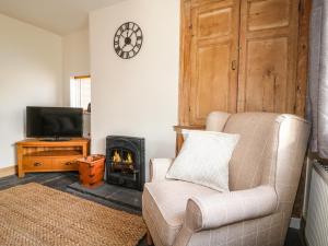 a living room with a chair and a fireplace at Hops Cottage in Ashbourne