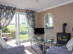 a living room with a couch and a tv and a window at Watergate Bay in Liskeard