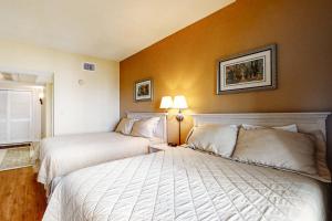 two beds in a hotel room with orange walls at Hotel Side Condo at Amelia Island Plantation with Balcony, WiFi & Shared Pool in Fernandina Beach