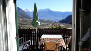 een tafel en parasol op een balkon met uitzicht op de bergen bij GRETL - Residence in Parcines