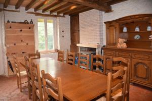 uma sala de jantar com uma mesa de madeira e cadeiras em Chez Maman em Beugnon