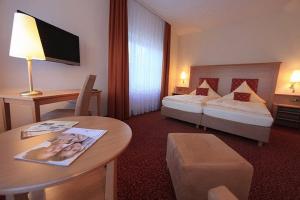 Cette chambre comprend 2 lits et une table. dans l'établissement Landhotel Möllhagen, à Schülp
