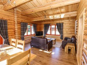 a log cabin living room with furniture and a table at Pine Lodge in Oakham