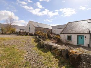 a group of buildings with rocks in front of a yard at Sweetheart Cottage in Dalbeattie