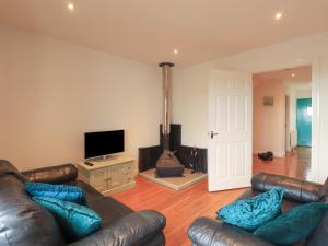 a living room with leather furniture and a flat screen tv at Sweetheart Cottage in Dalbeattie