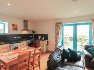 a kitchen and living room with a table and a couch at Sweetheart Cottage in Dalbeattie