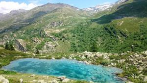 un lac bleu au milieu d'une montagne dans l'établissement Bel appartement au pied des pistes, à Valmeinier 5 autres photos
