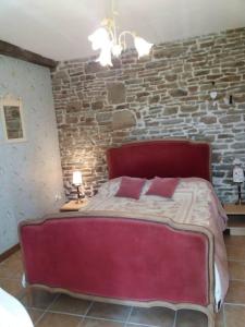 a red bed in a room with a stone wall at Captivating 2-Bed Cottage in Mortain-Bocage in Notre-Dame-du-Touchet