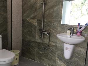 a bathroom with a shower with a sink and a toilet at Hana Riverside Villa in Quang Ngai